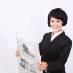 新聞を広っげる女性
