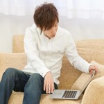 ソファーでパソコンを持っている男性